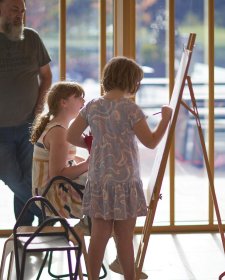 Two children drawing at an easel in the Gordon Darling Hall