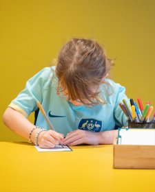 A child drawing at a yellow table