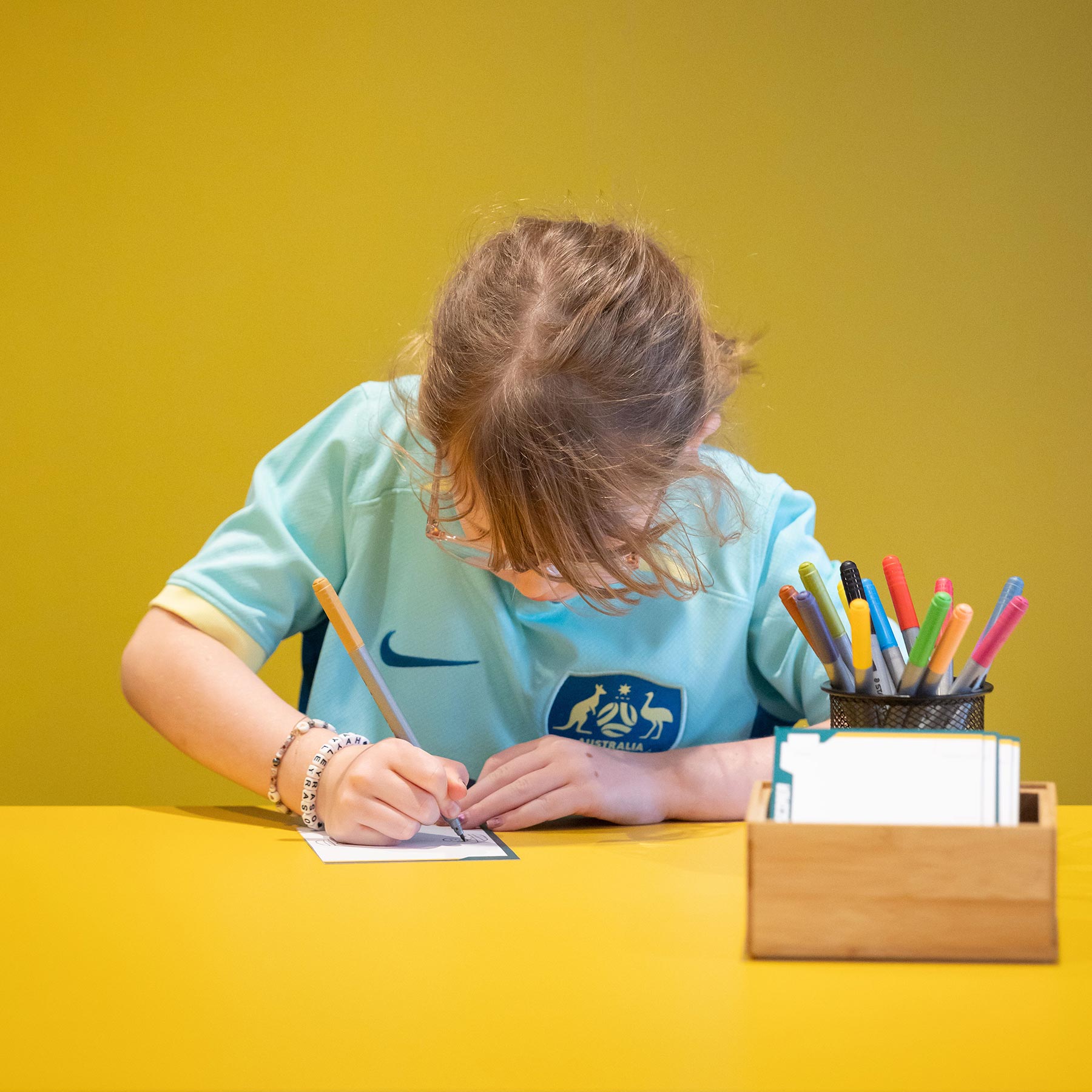 A child drawing at a yellow table