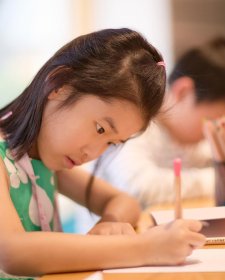 A child drawing at a wooden table