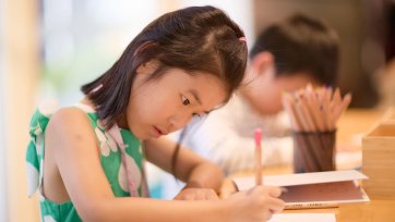 A child drawing at a wooden table