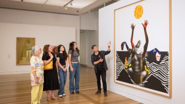 People looking at an artwork (Marcia Langton by Brook Andrew) in the Gallery