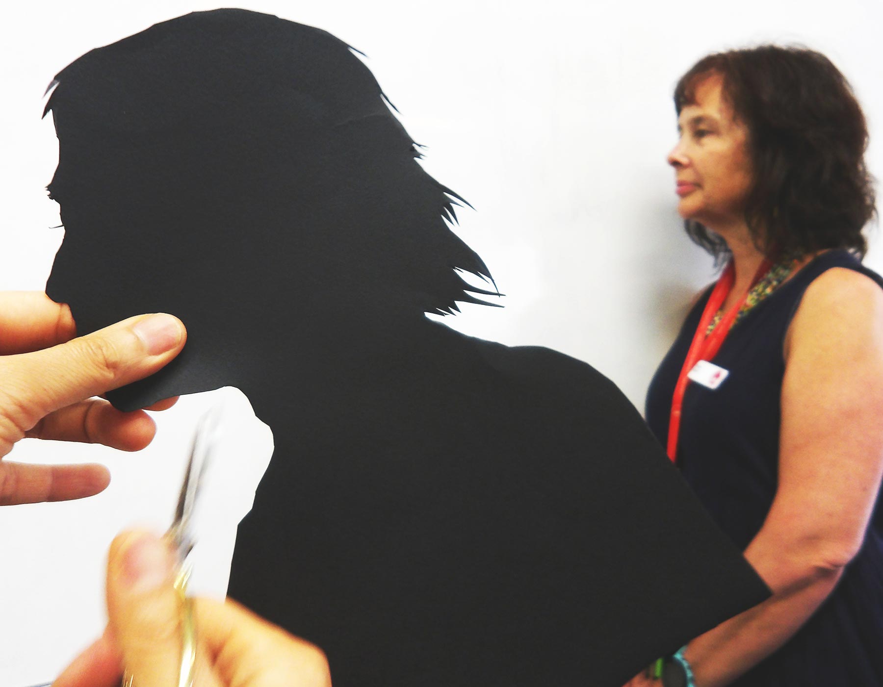 Cutting out a paper silhouette in the shape of a head